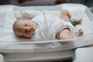 A newborn baby is sleeping in a hospital bed.