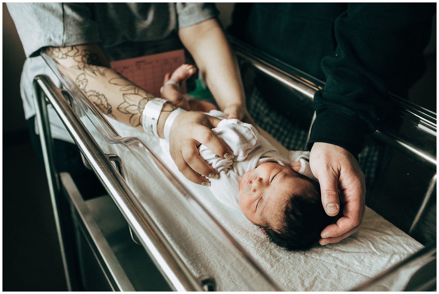 A man and woman are holding a newborn baby in a hospital crib.