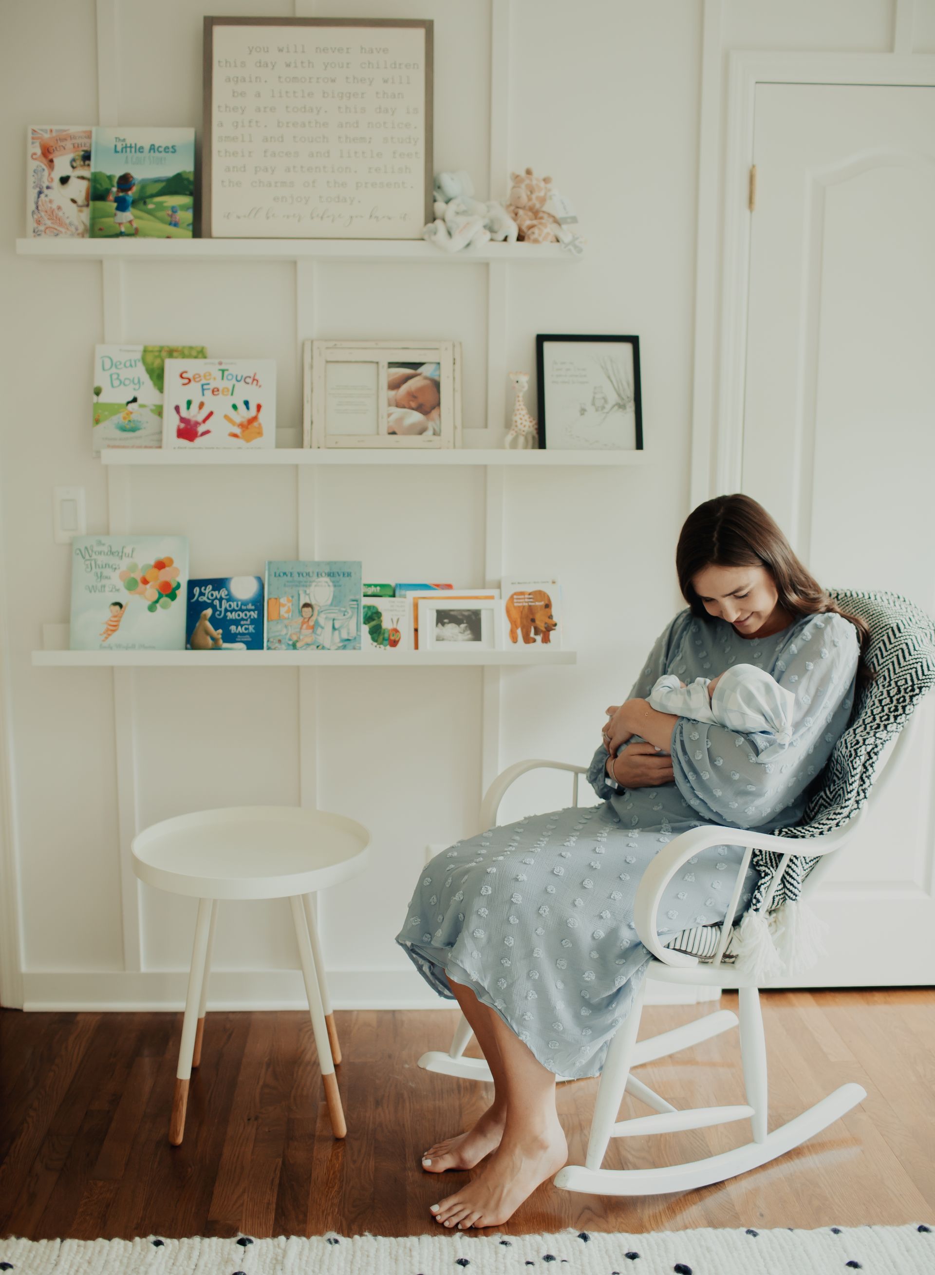 A woman is sitting in a rocking chair holding a baby.