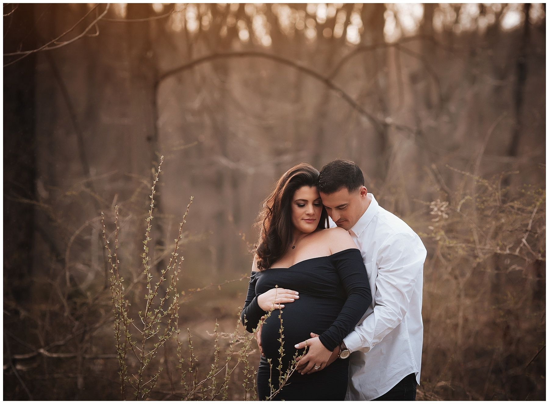 A man is hugging a pregnant woman in a field.