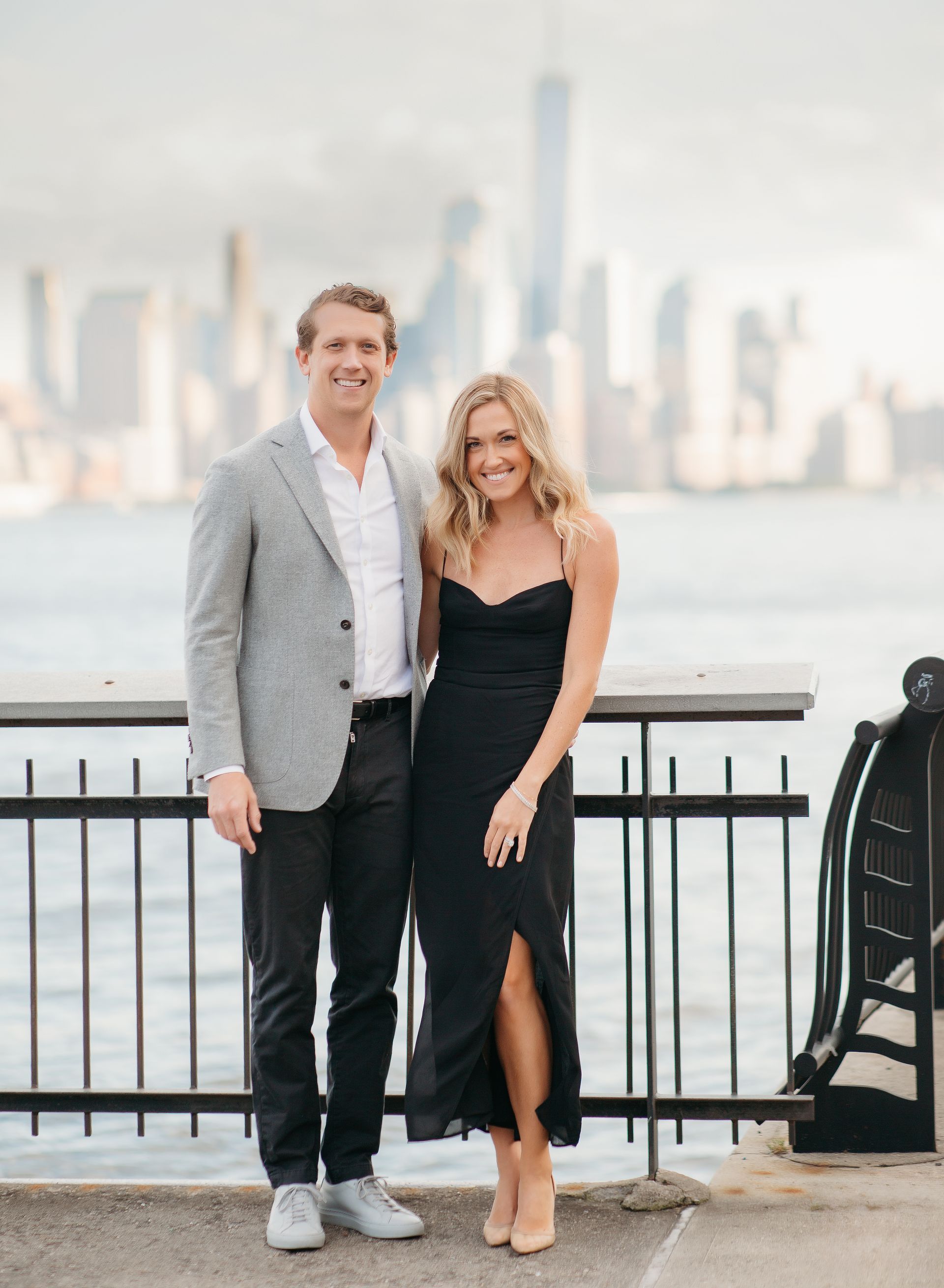 A man and a woman are standing next to each other in front of New York City Skyline