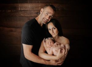 A man and woman are holding a newborn baby in their arms.