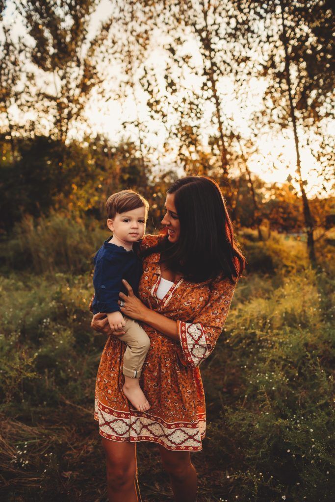 A woman is holding a baby in her arms in a field.