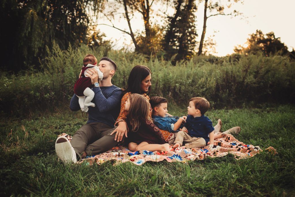 A family is sitting on a blanket in the grass.