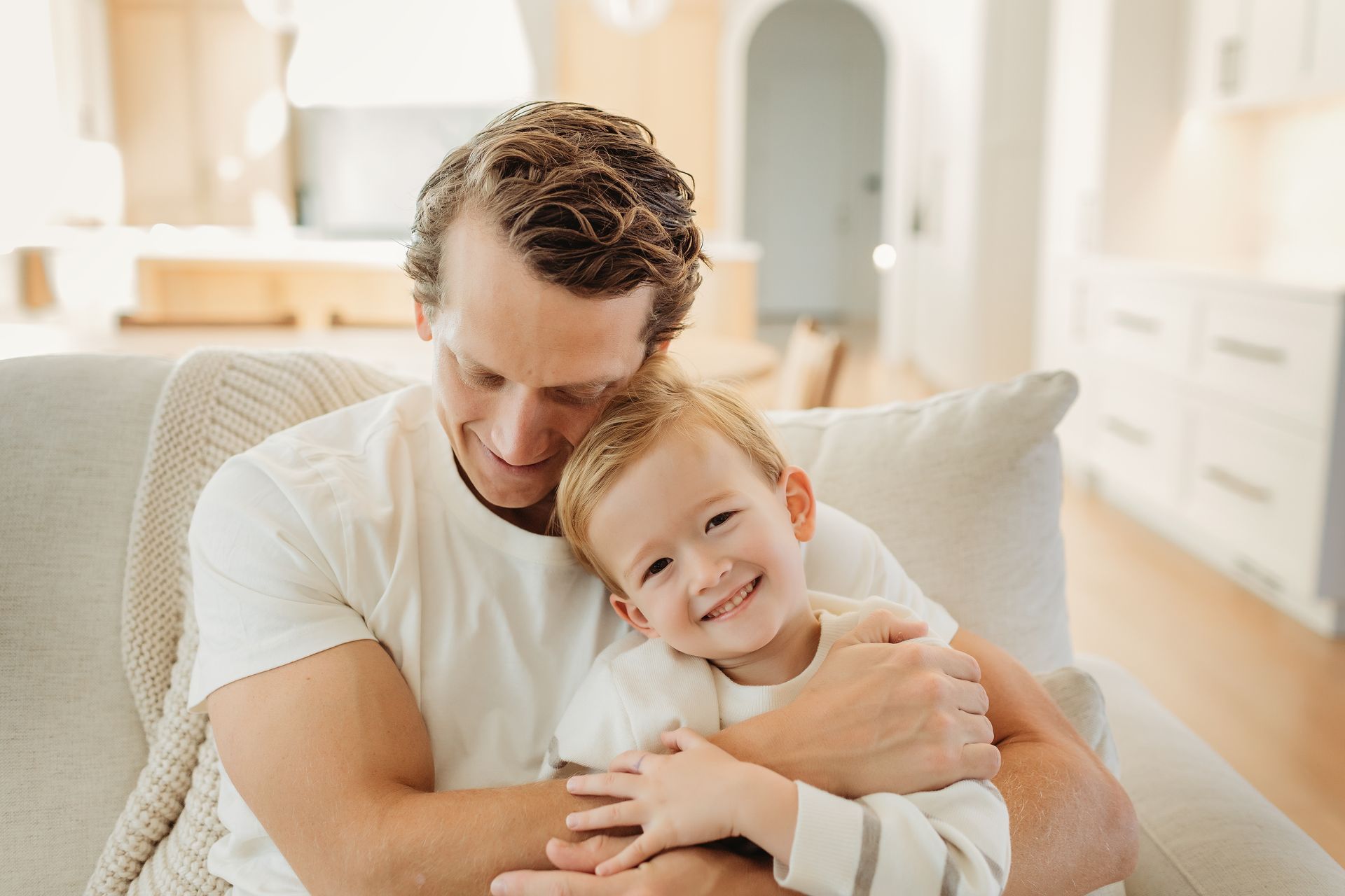 A man is sitting on a couch holding a little boy.