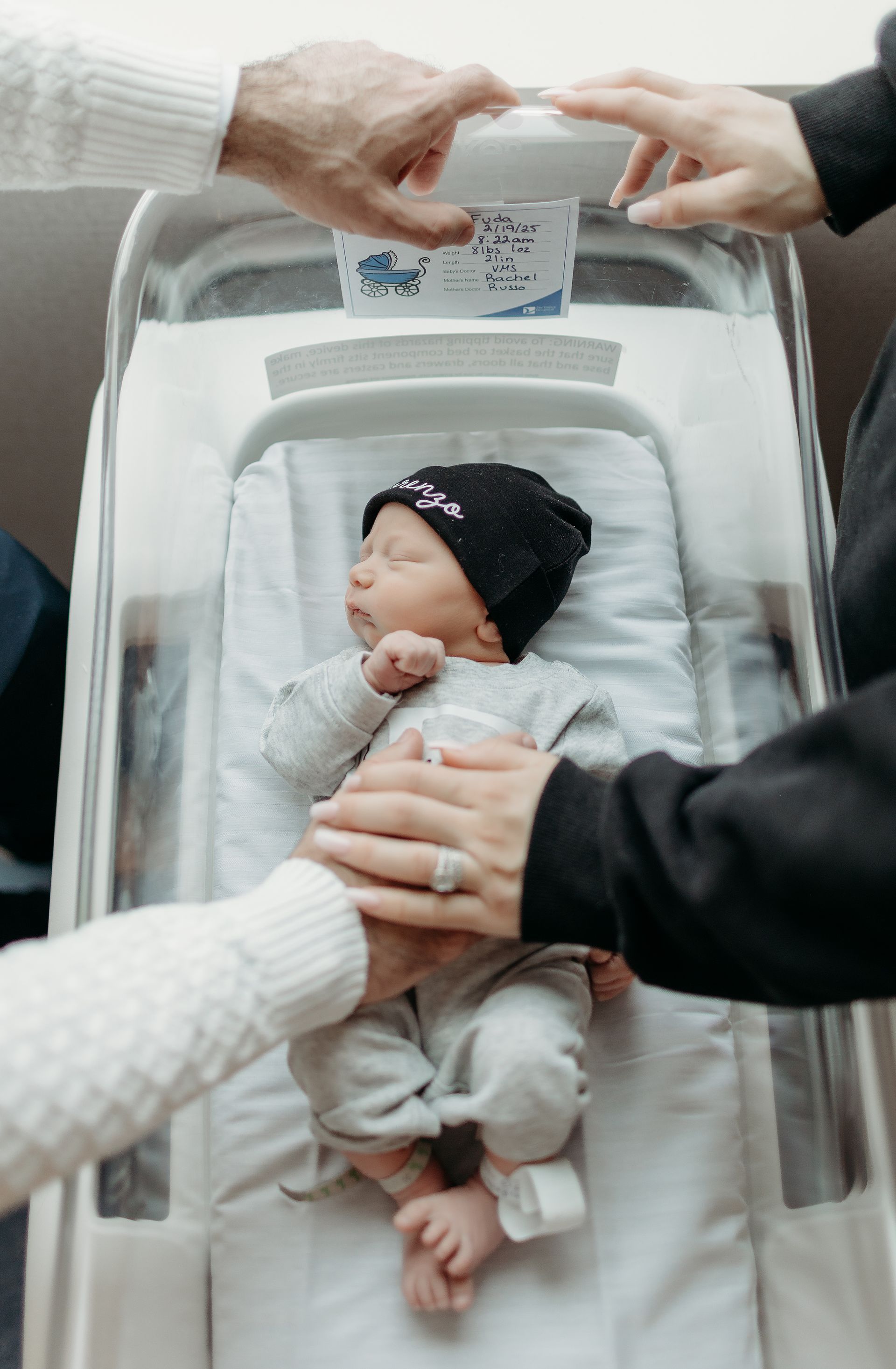 A couple is holding a newborn baby in a hospital bed.
