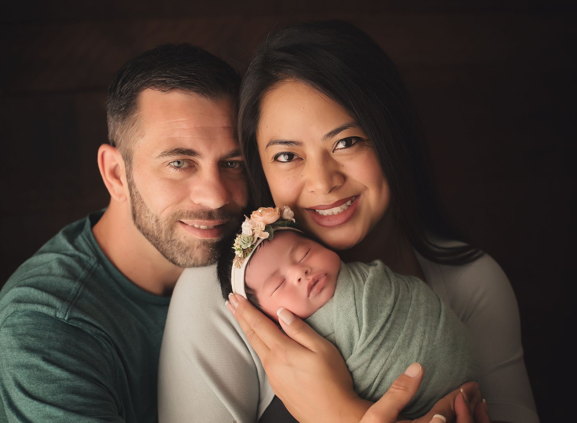 A man and woman are holding a newborn baby in their arms.