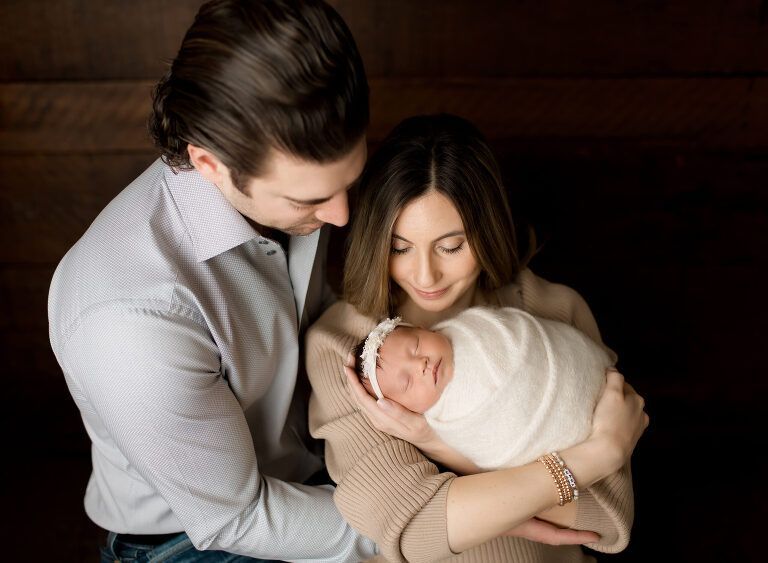 A man and woman are holding a newborn baby in their arms.
