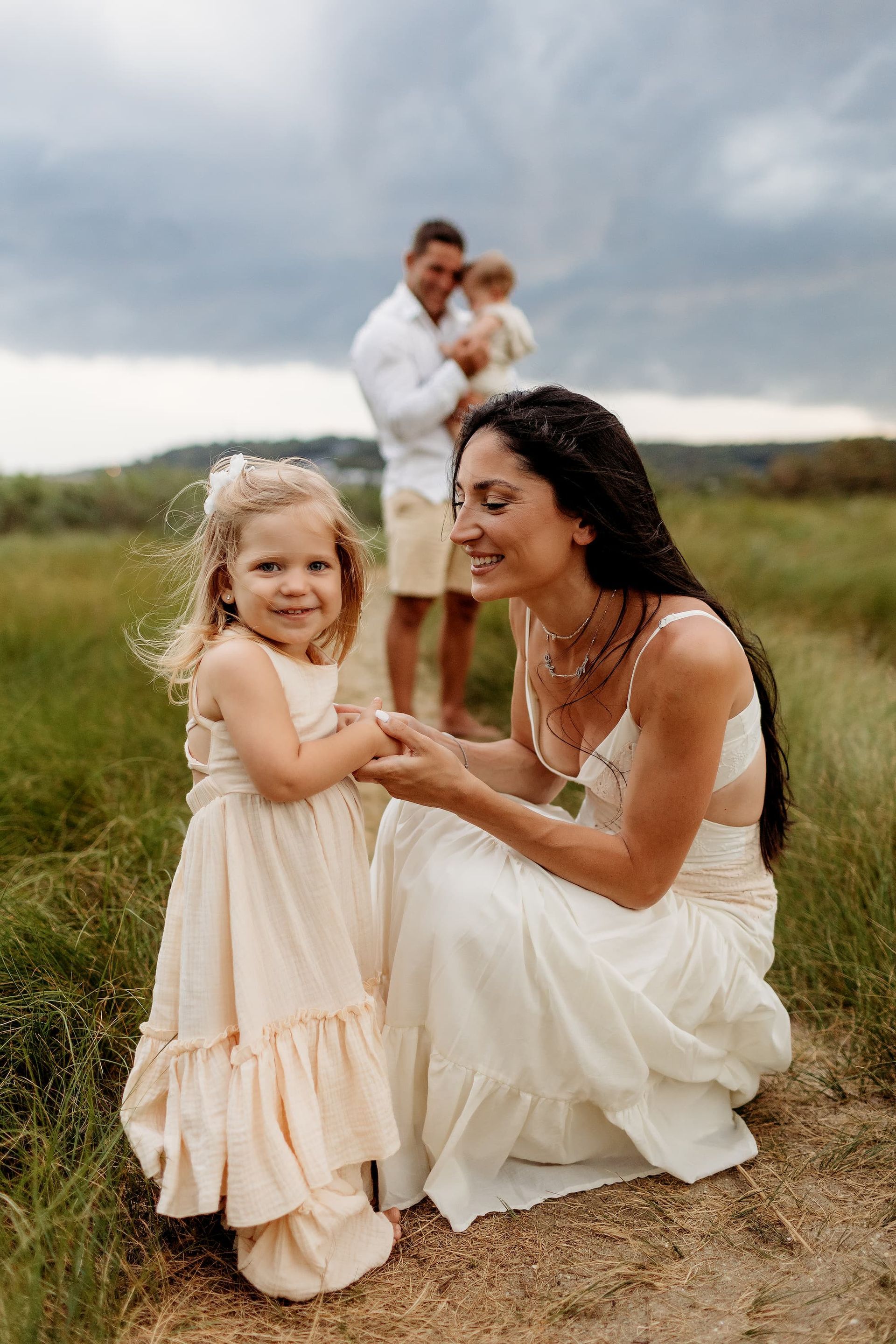 Family embracing on a beach at sunset. Children and adults laugh, enjoying each other's company on sandy shore.