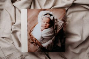 A picture of a baby wrapped in a blanket is sitting on a bed.
