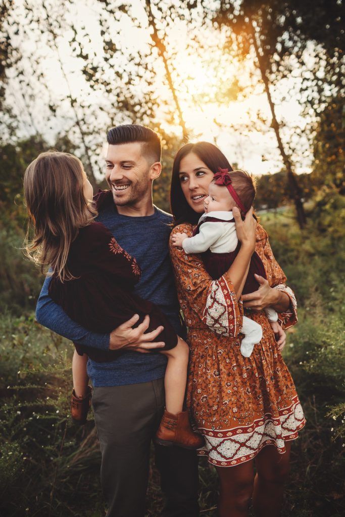 A family is posing for a picture in the woods.