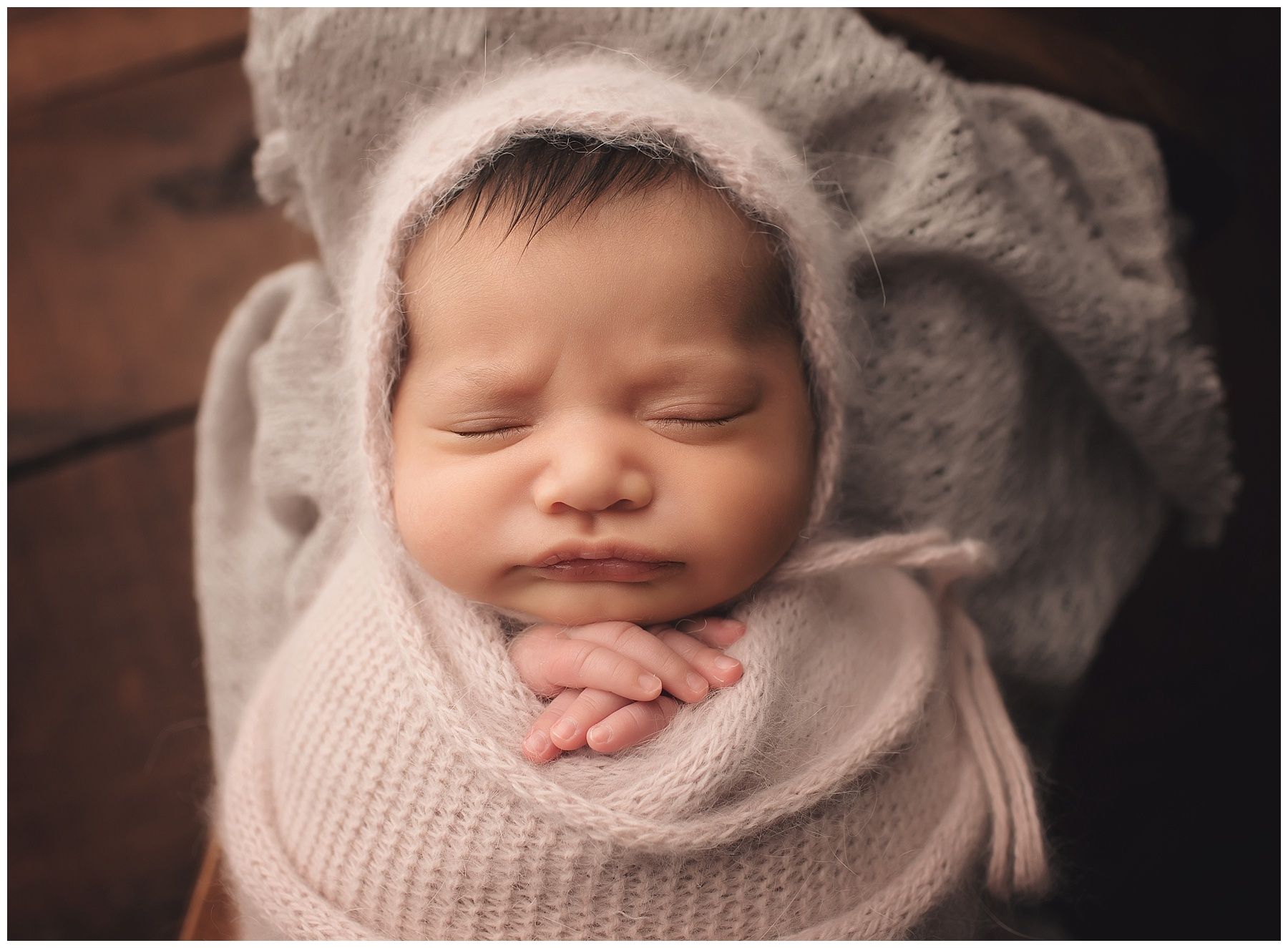 A newborn baby is wrapped in a blanket and wearing a hat.