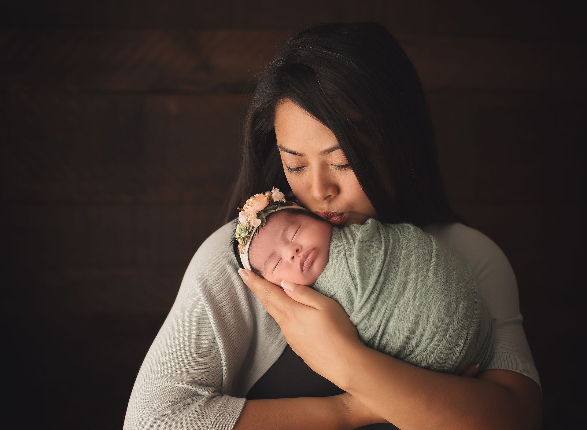 A woman is holding a newborn baby wrapped in a blanket.