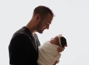 A man is holding a newborn baby in his arms.