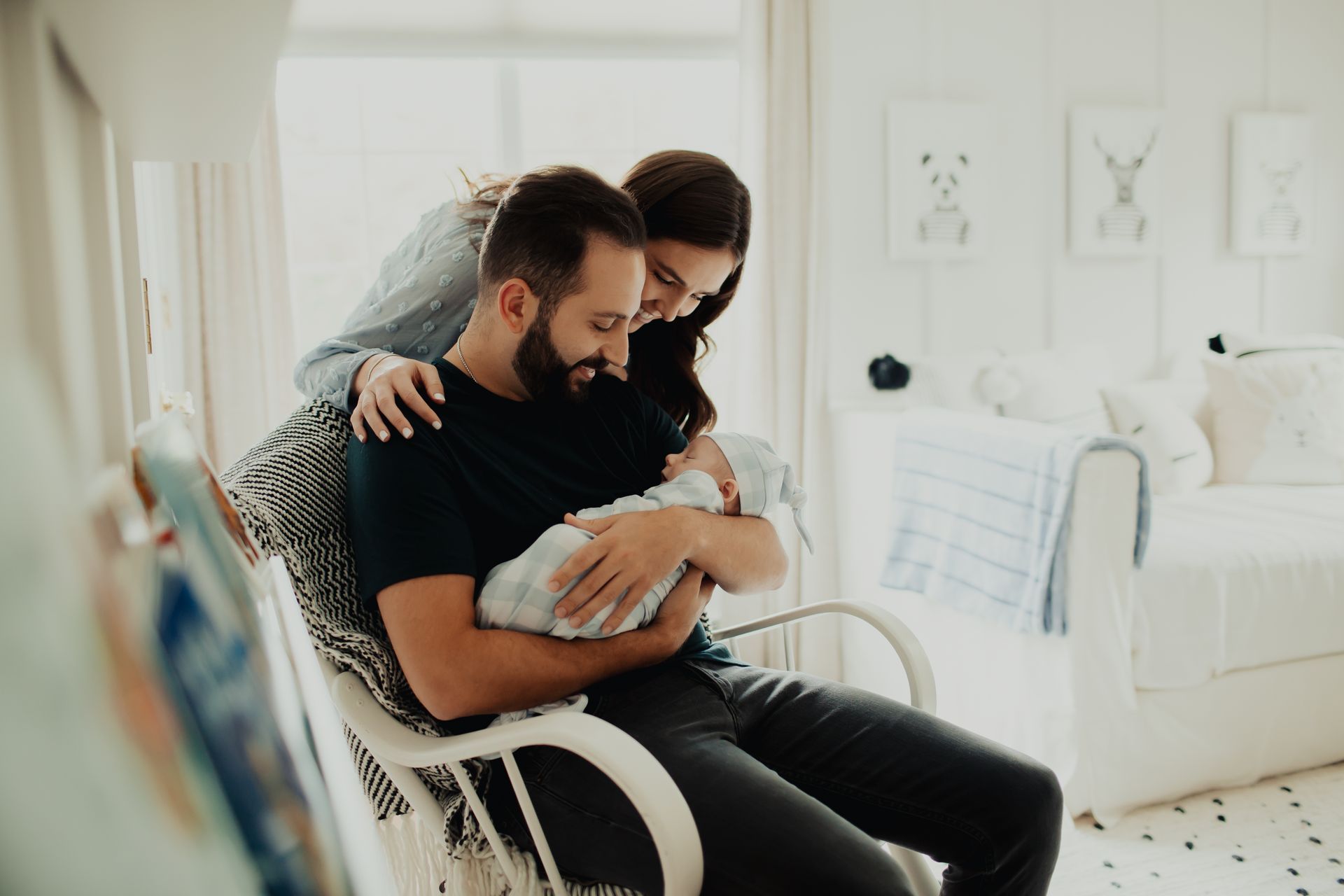 A man and woman are holding a newborn baby in a rocking chair.