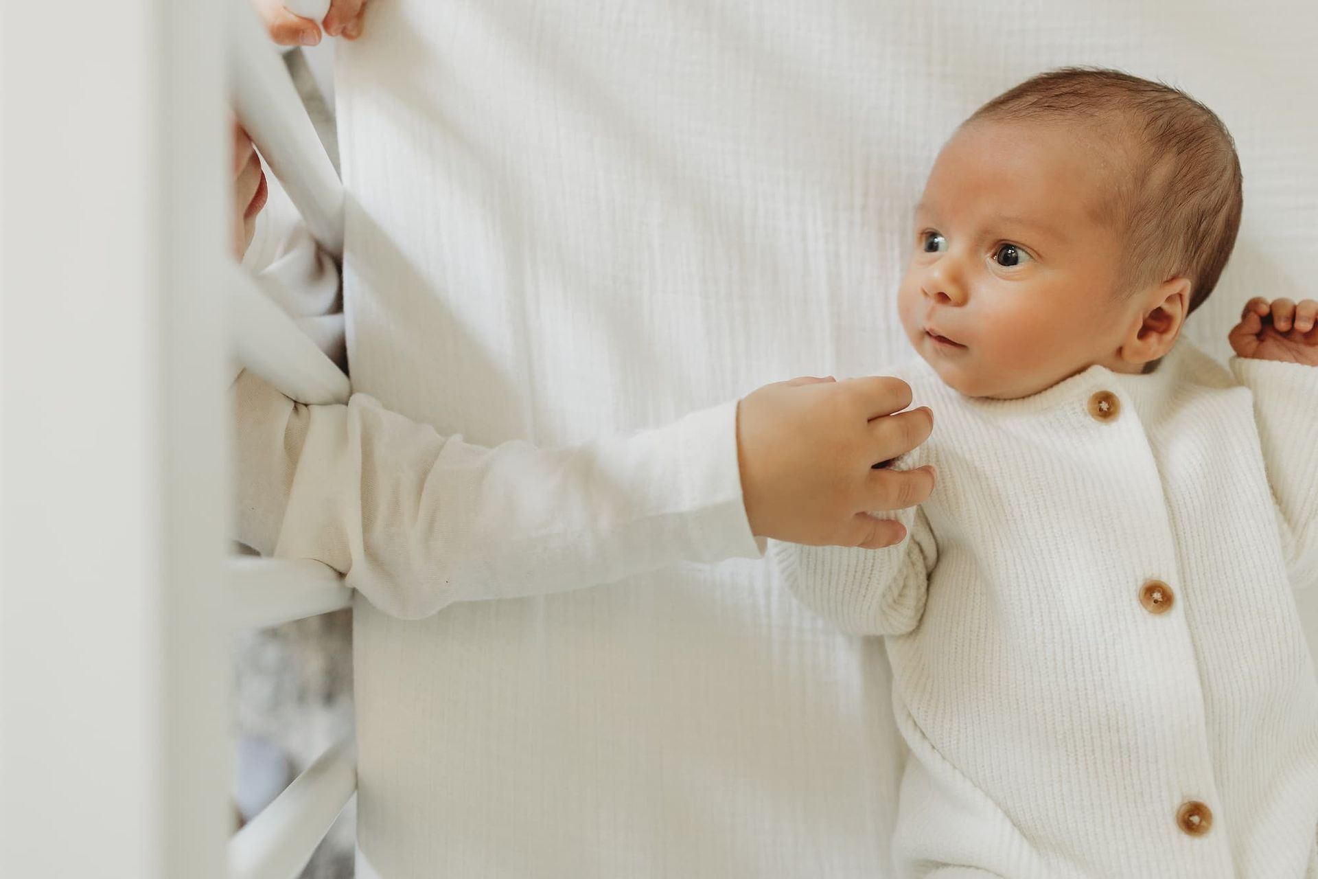 Toddler looking into crib at newborn sibling during in-home newborn session in Ridgewood NJ