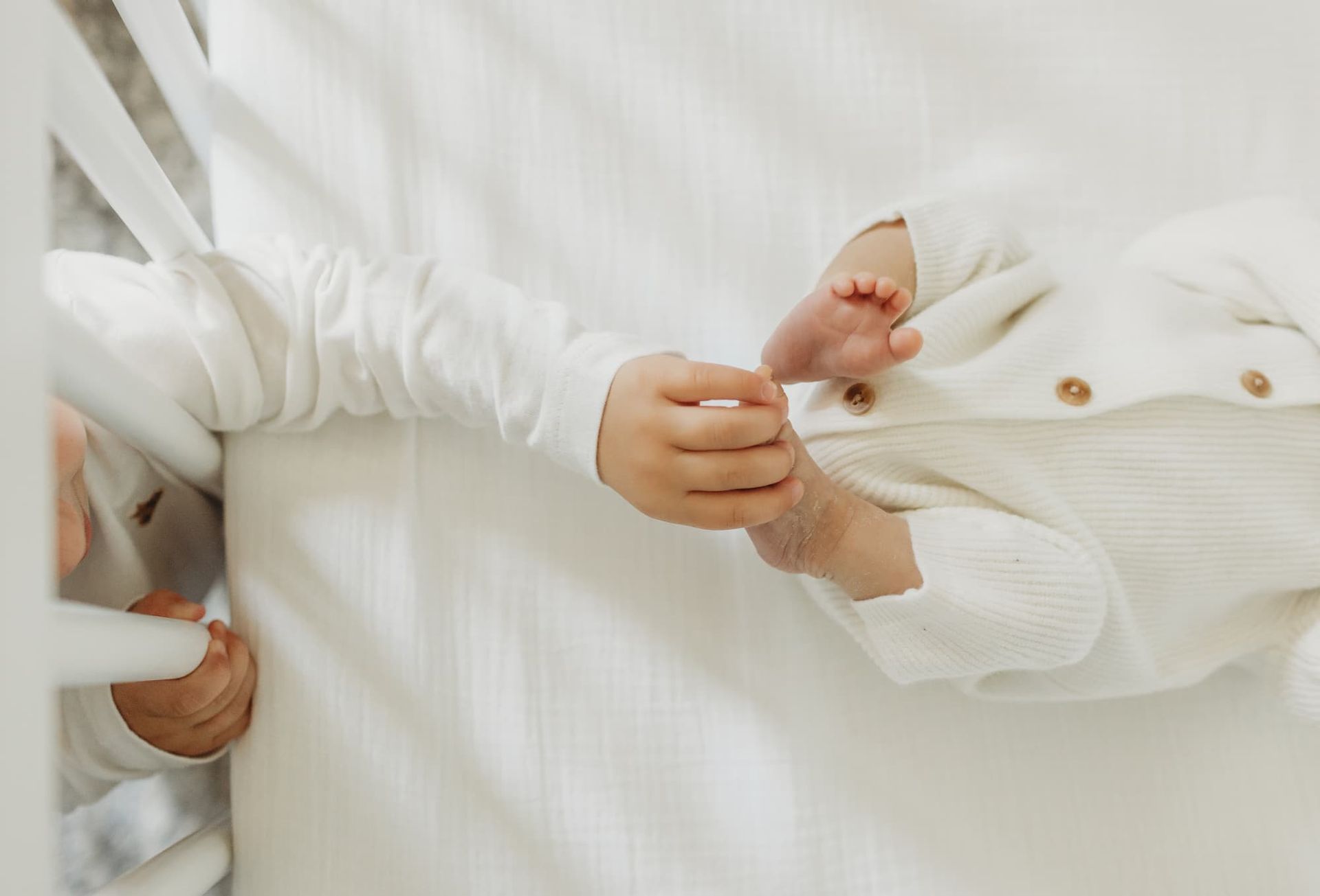 Sibling gently touching newborn baby feet during lifestyle newborn session in Ridgewood NJ