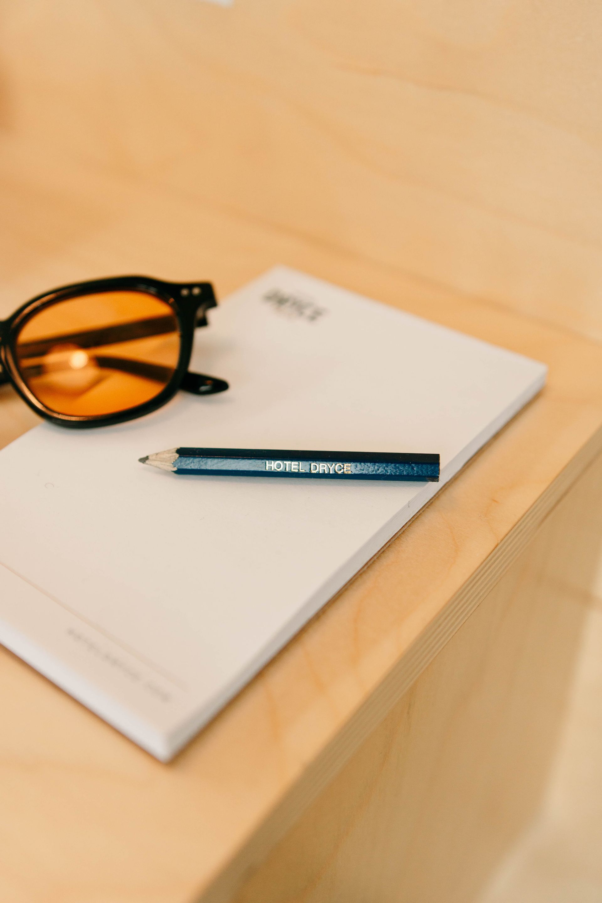 A pencil is sitting on top of a piece of paper next to a pair of sunglasses.