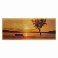 Sunset over water with a bench, lone tree, and golden sky.