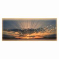 Sun's rays burst through clouds at sunset, painting the sky with orange and blue hues.