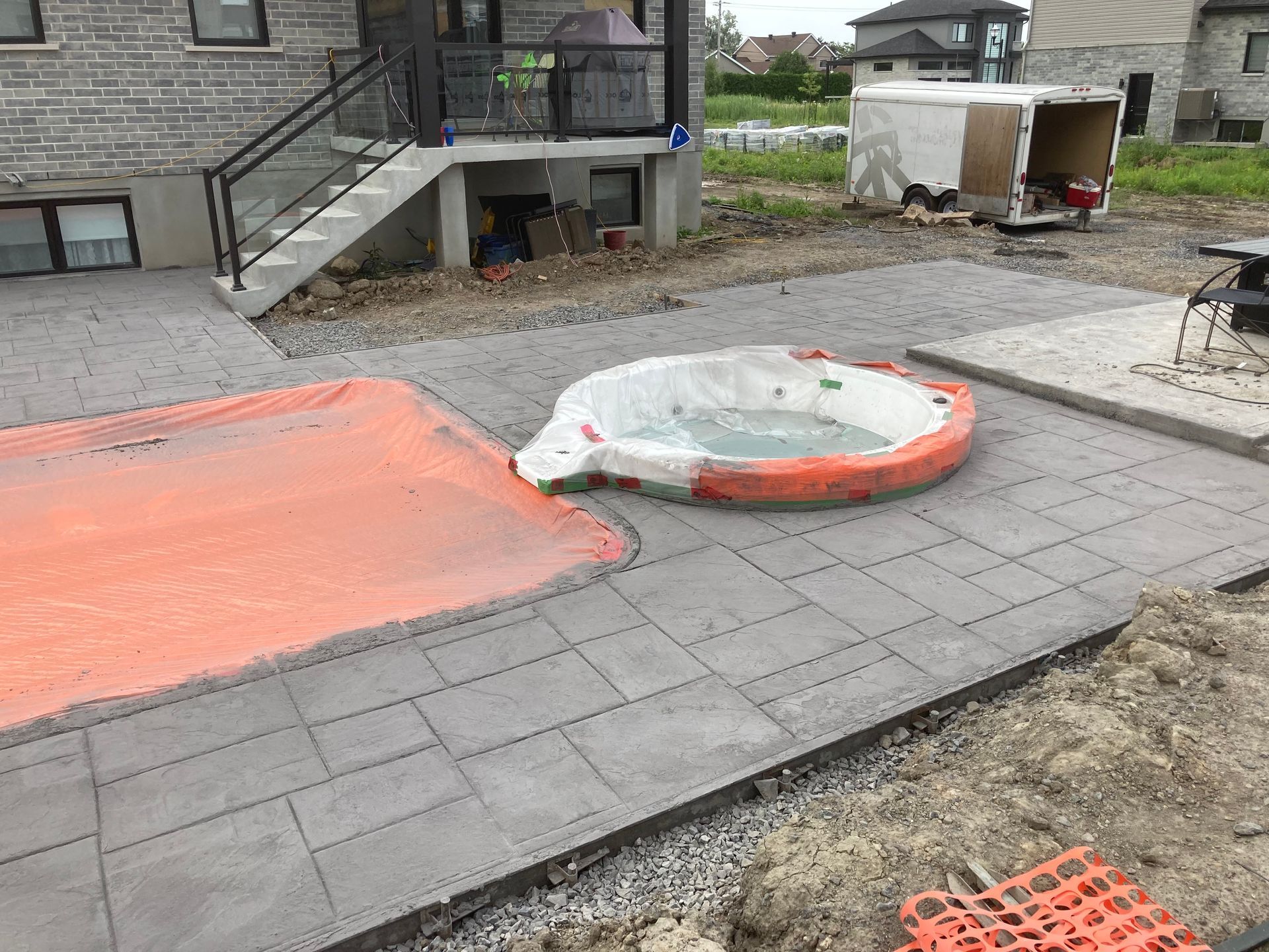 Un bain à remous est installé sur une terrasse en béton à côté d'une maison.