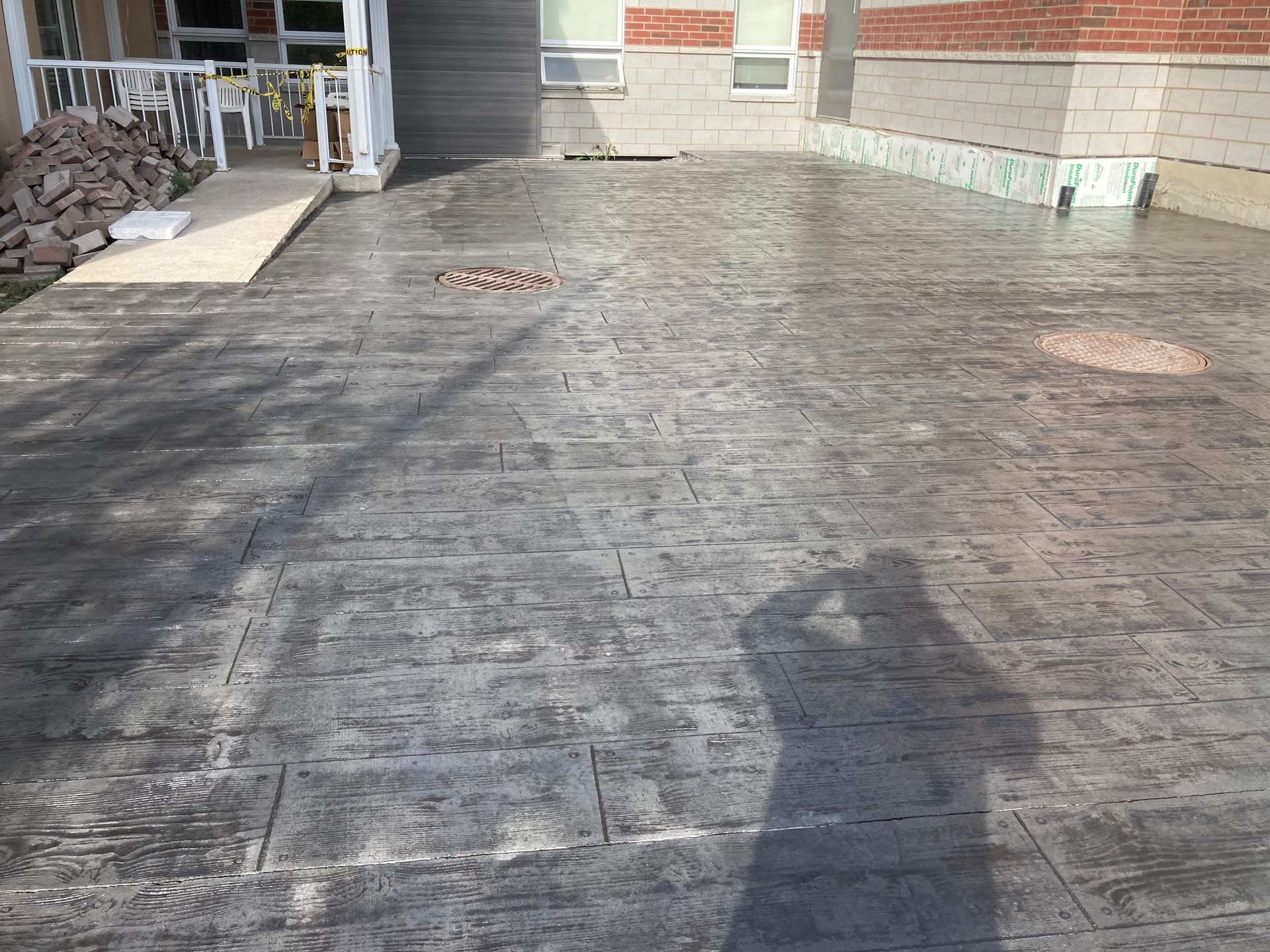 L'ombre d'une personne est projetée sur une allée en béton devant une maison.