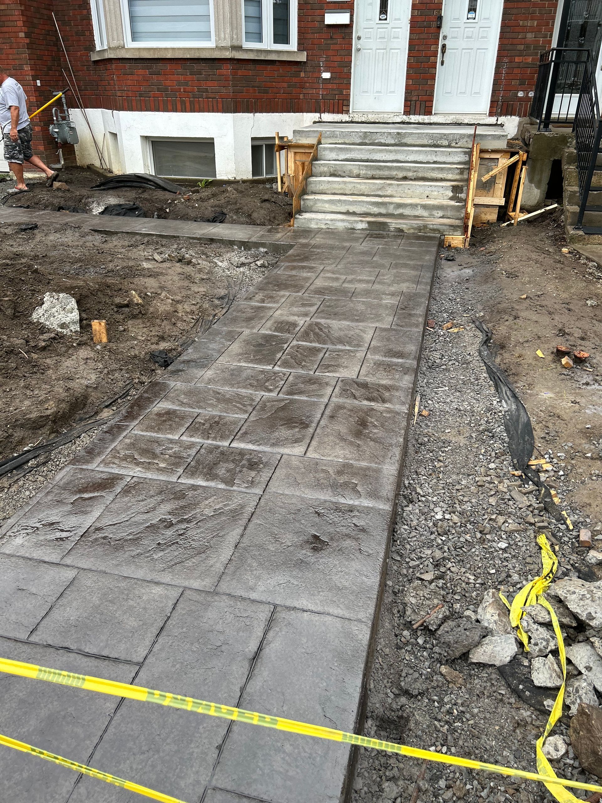 Un trottoir est en cours de construction devant un bâtiment en briques.