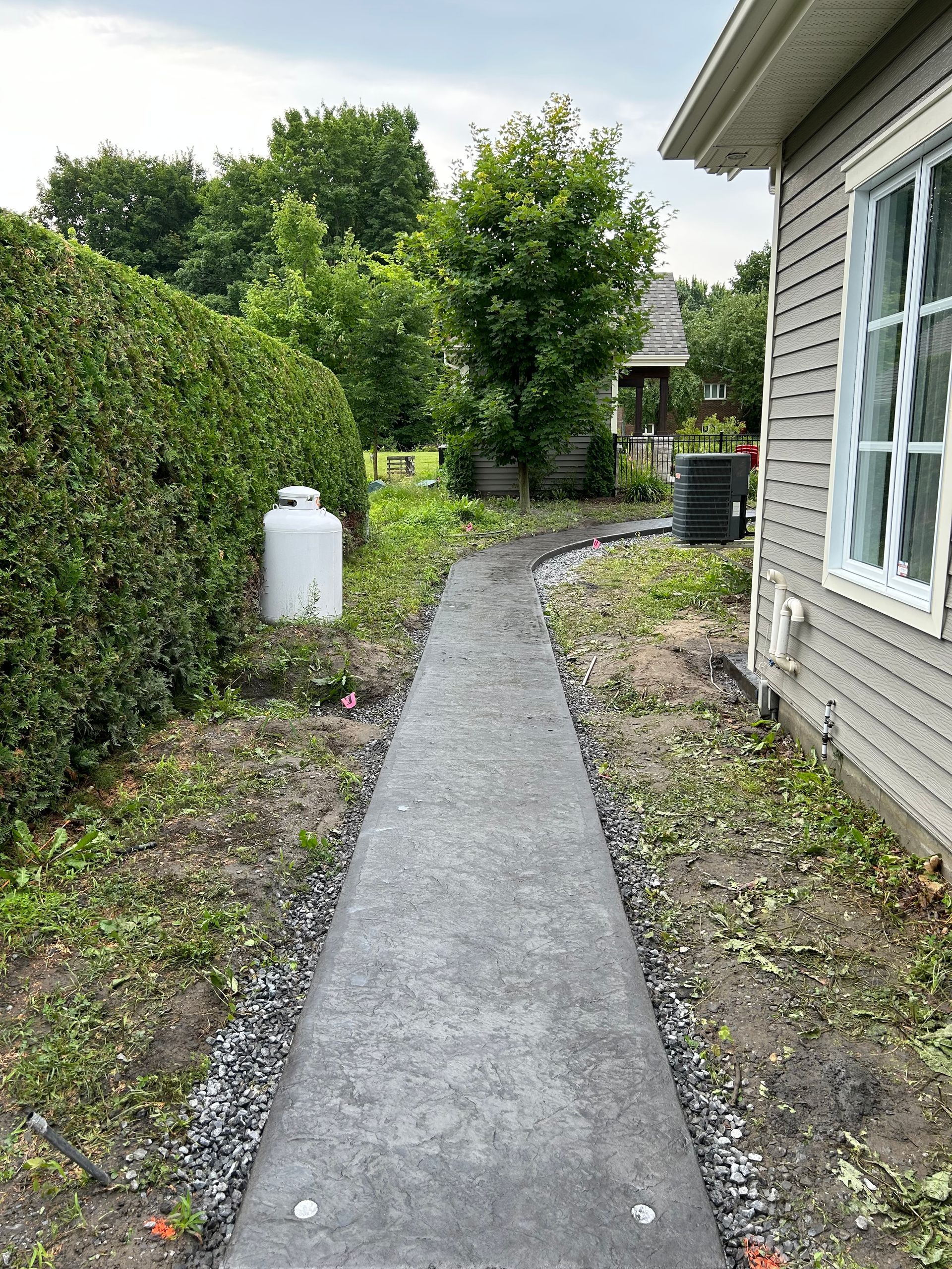 Une allée en béton menant à une maison dans l'arrière-cour.
