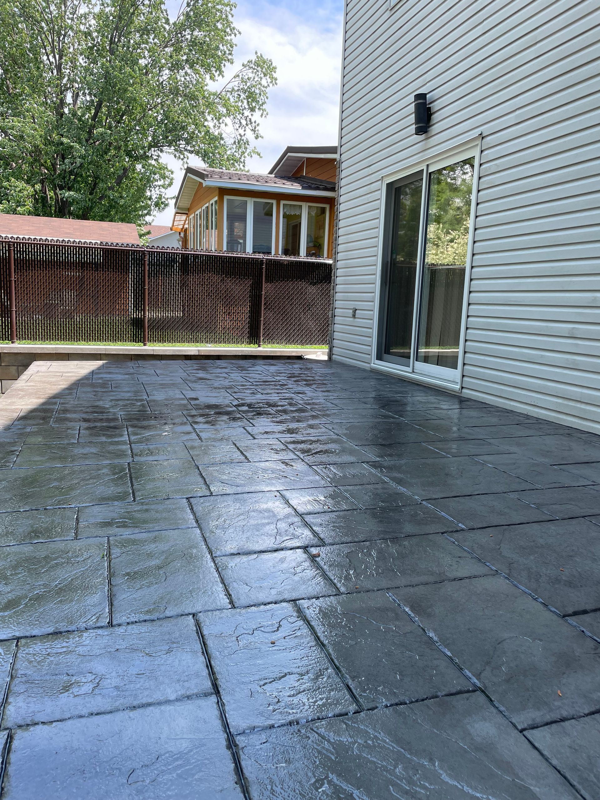Un patio avec une porte coulissante en verre dans l'arrière-cour d'une maison.