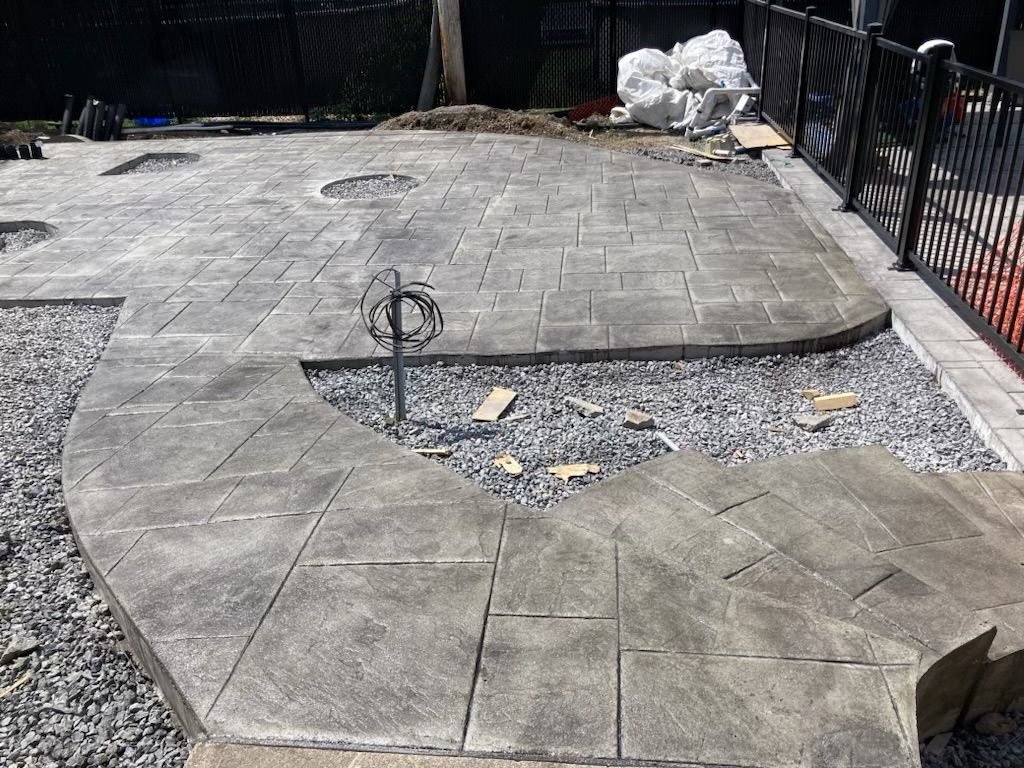 Un patio en béton avec une clôture en arrière-plan est en cours de construction.