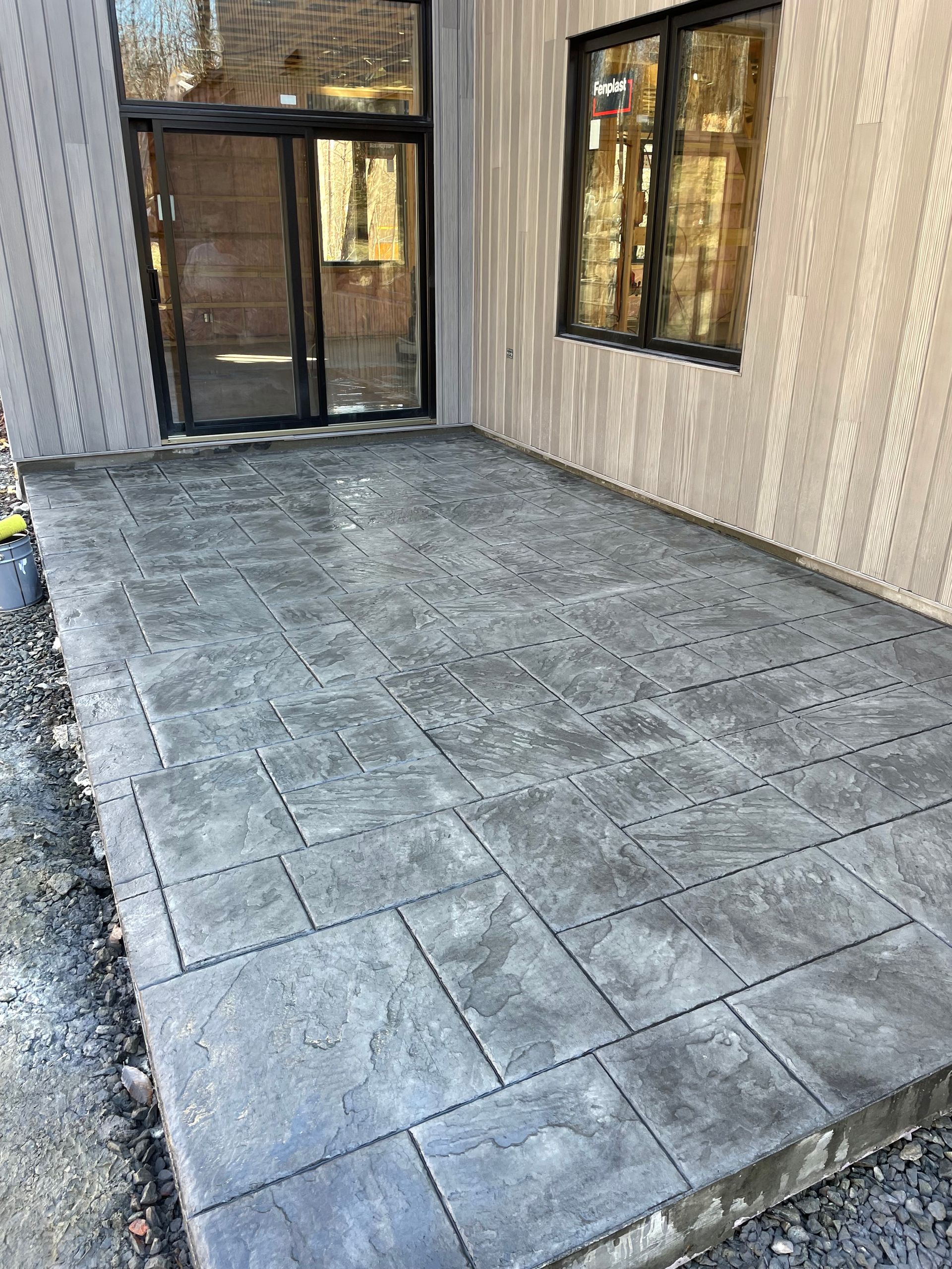 Un patio en béton devant une maison avec une porte coulissante en verre.