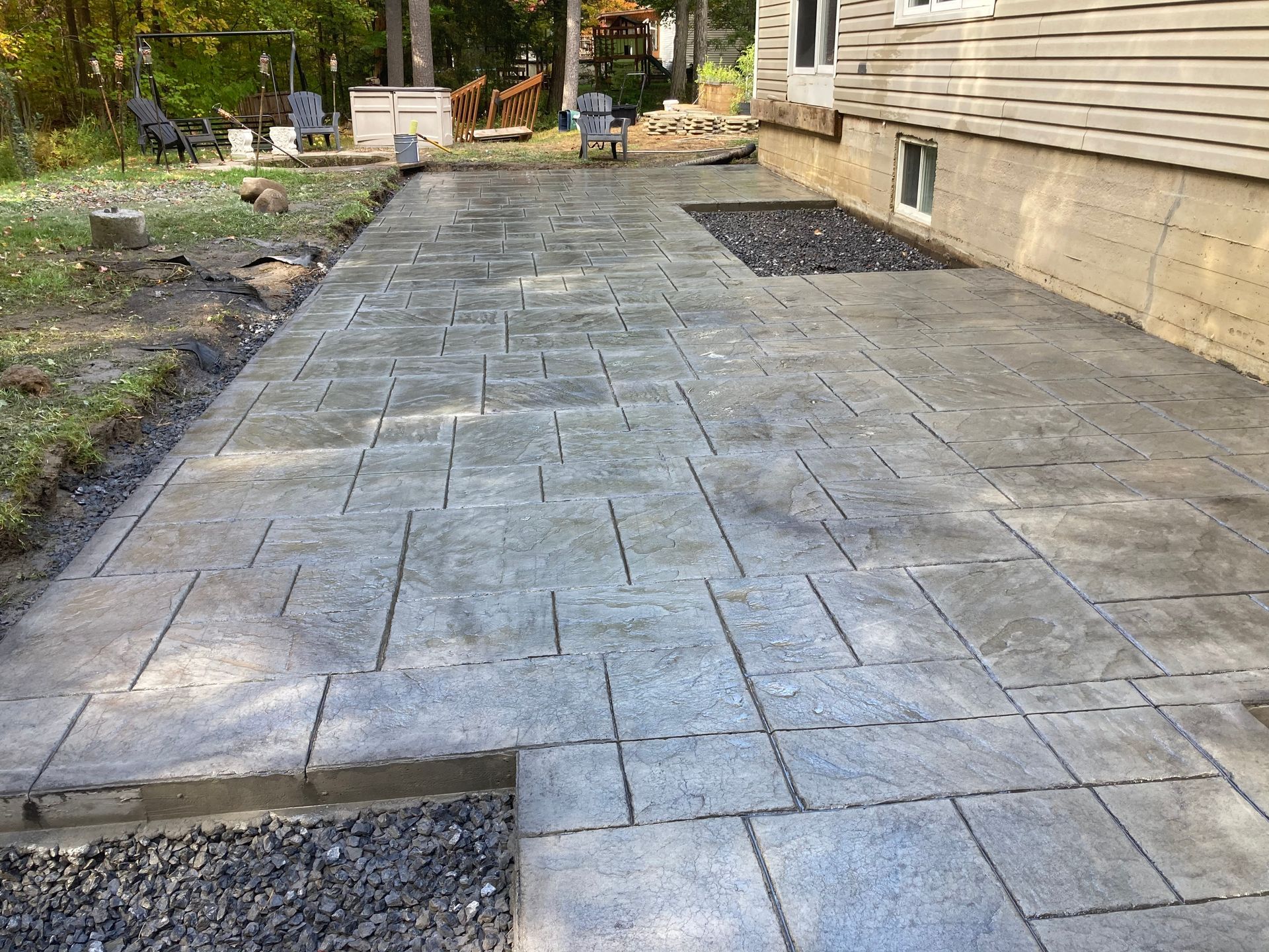 Un patio en béton est en cours de construction devant une maison.