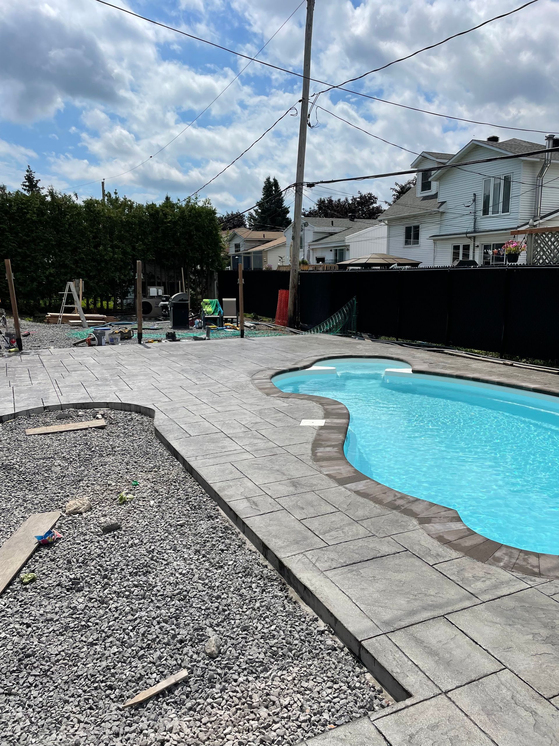 Une grande piscine est entourée de gravier et d'une clôture