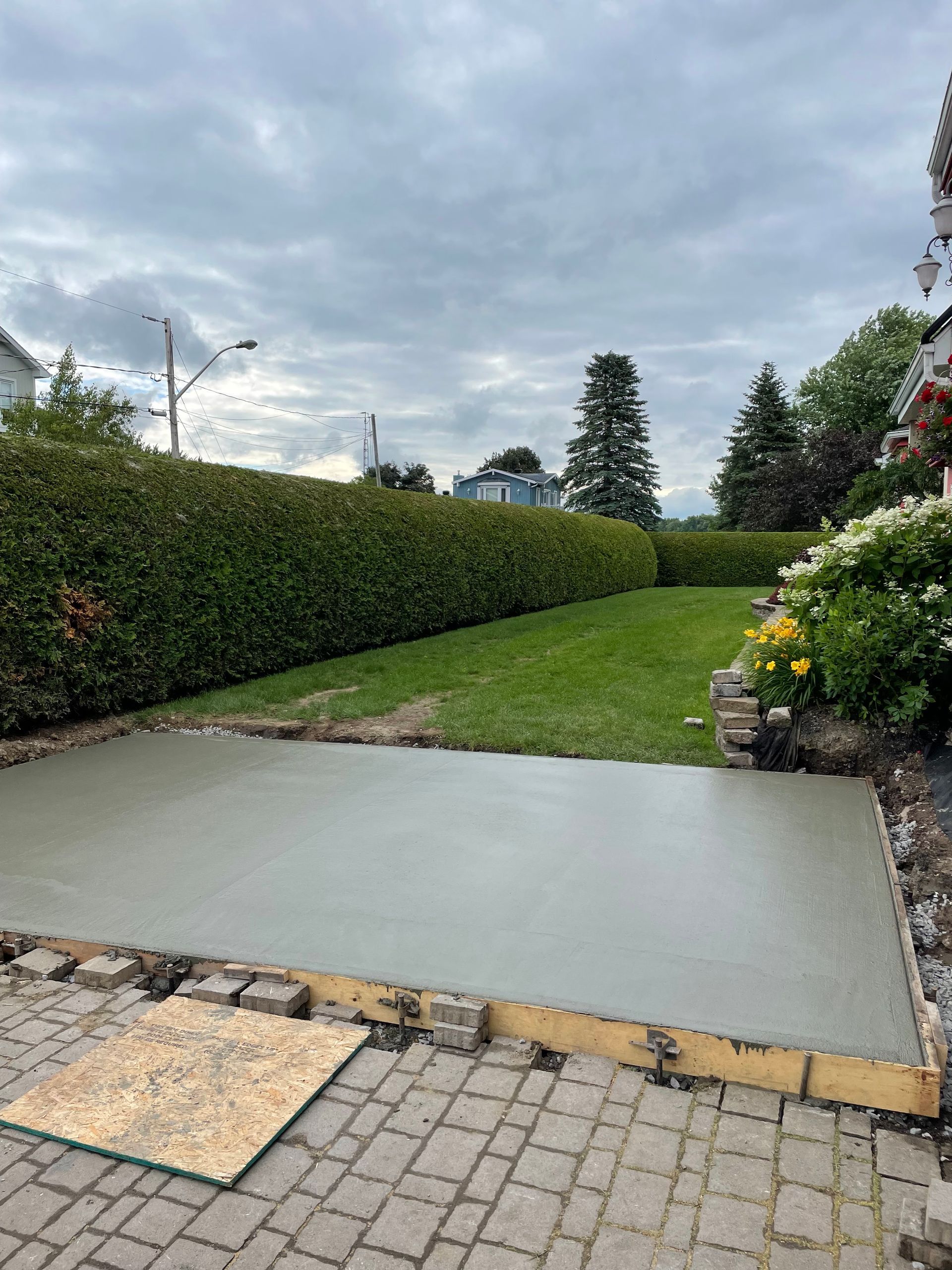 Une allée en béton est en cours de construction dans une cour arrière.