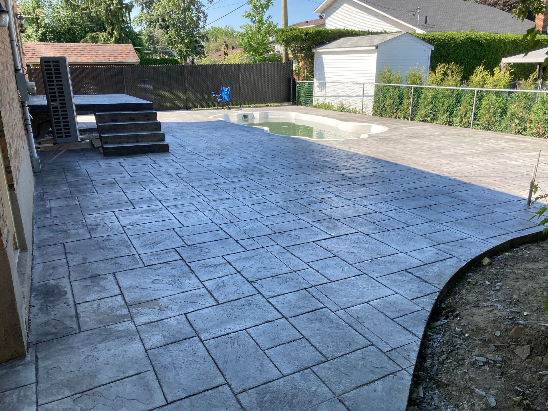 Un patio avec une piscine en arrière plan et une maison en arrière plan.