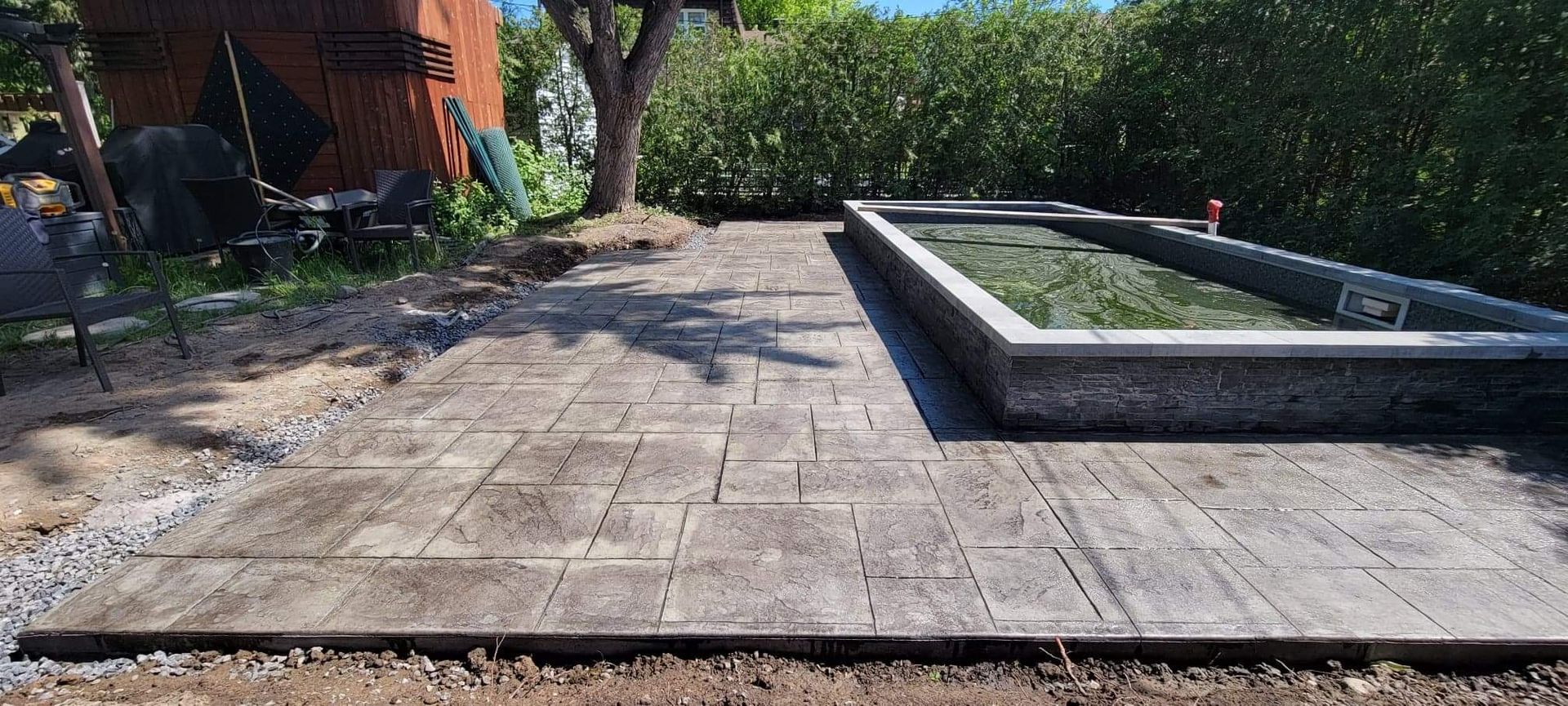 Un patio avec un étang en arrière-plan et un cabanon en arrière-plan.