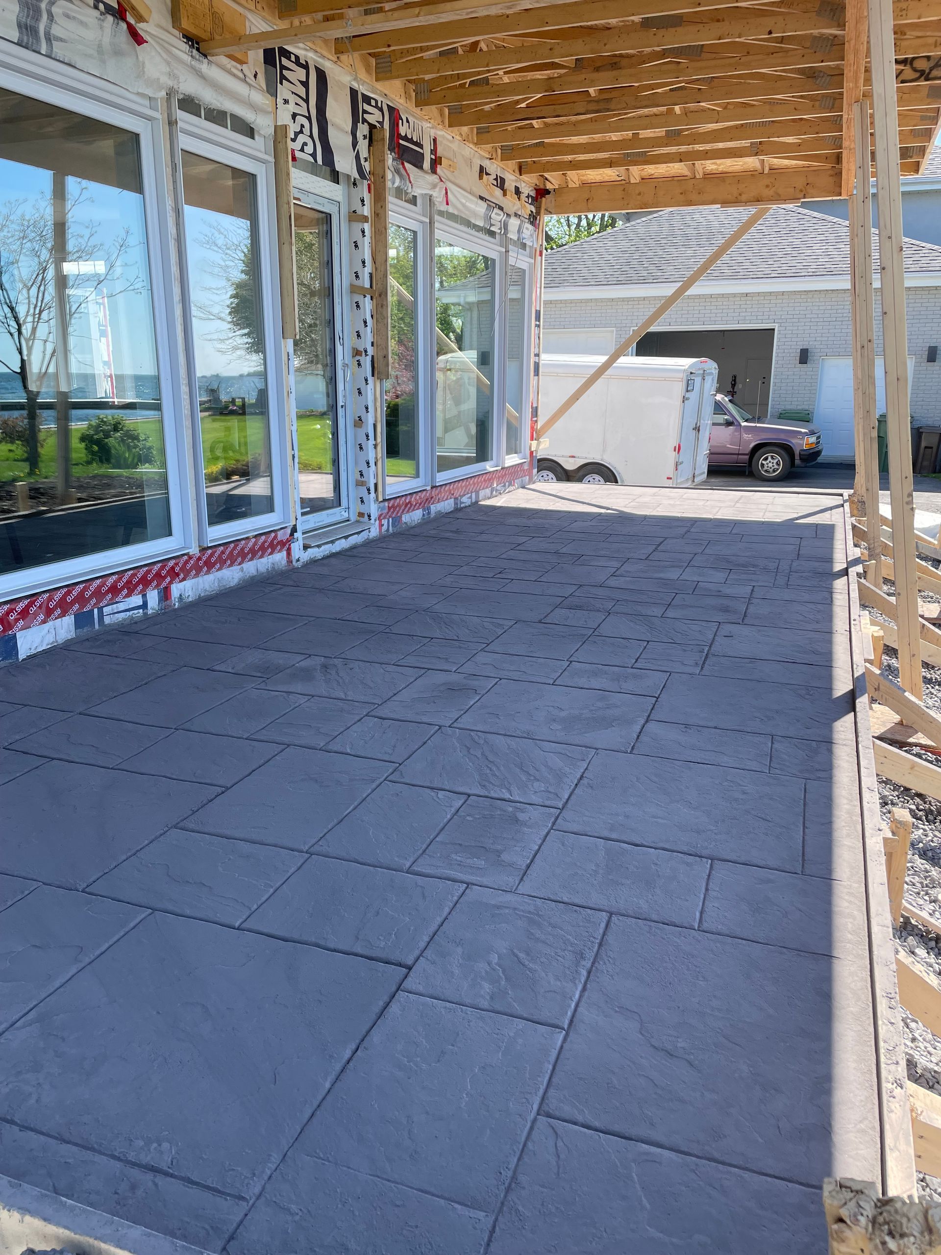 Une maison est en construction avec un porche couvert et beaucoup de fenêtres.