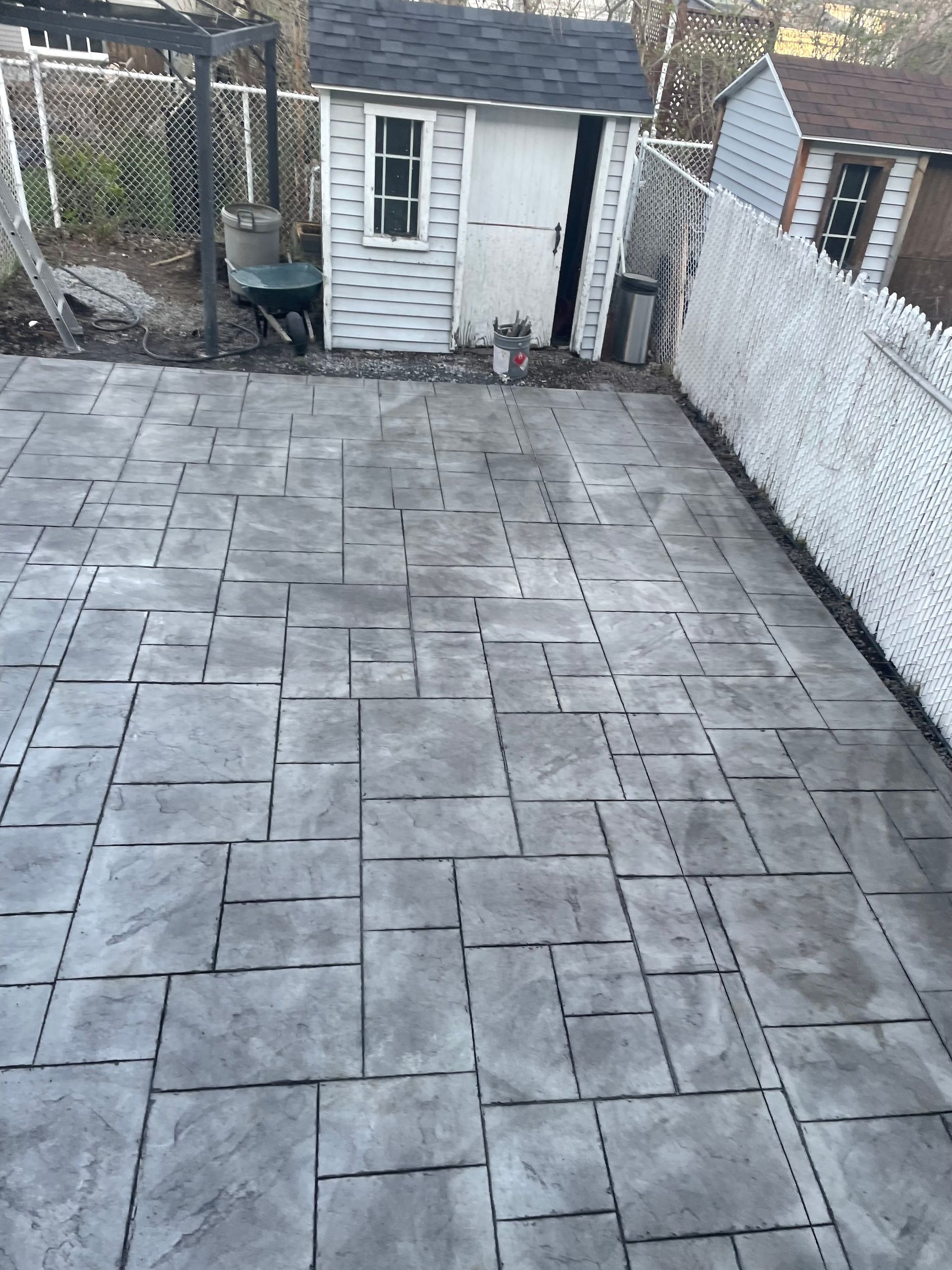 Un patio en béton avec un cabanon en arrière-plan