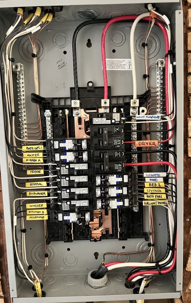 Electrical switchgear control room with rows of gray panels, yellow floor lines, and blue shelving.