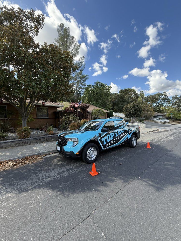 An electrician in a hard hat and safety vest working on electrical components inside a panel.