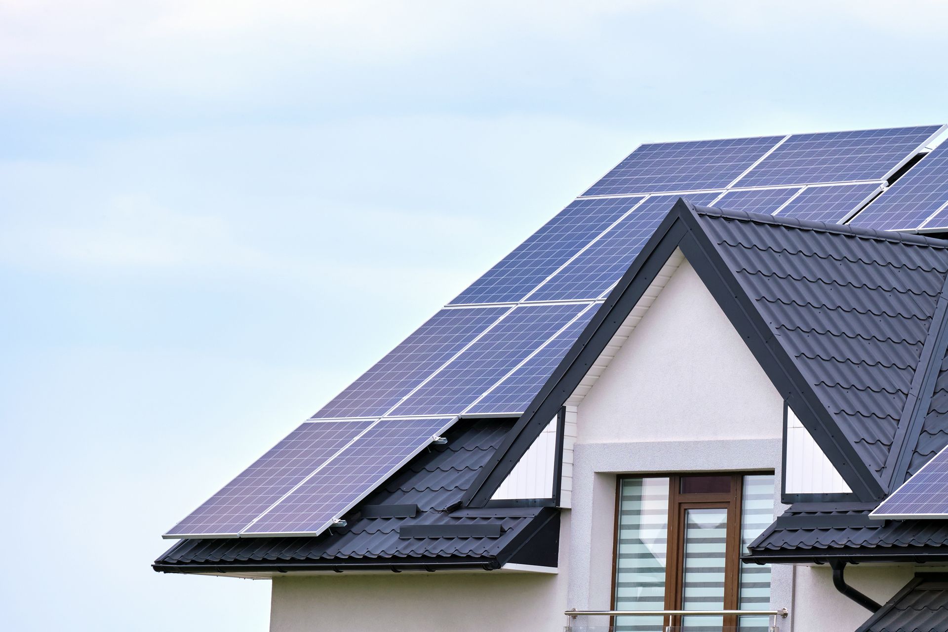 Solar panels on a house roof, against a blue sky.