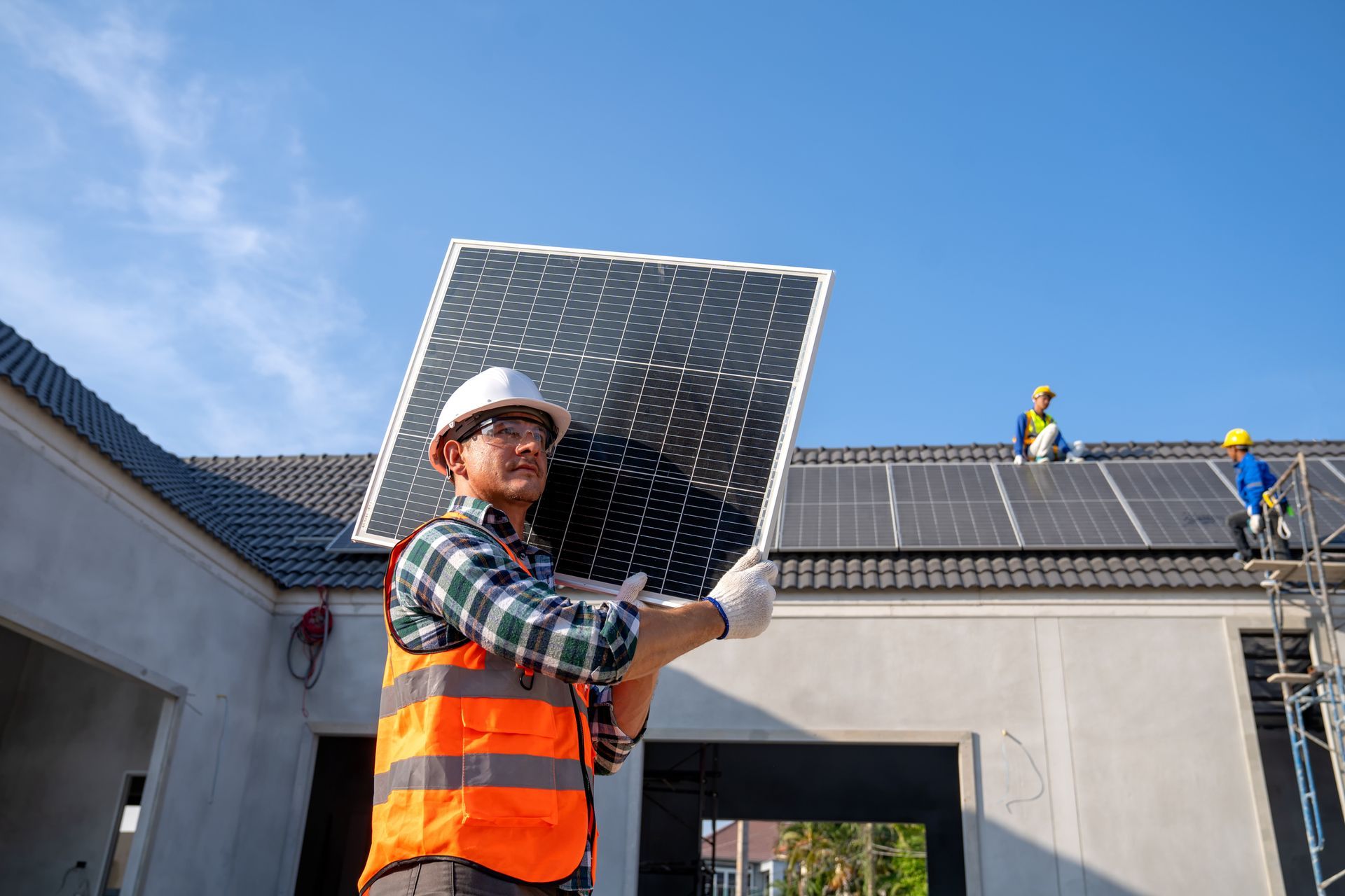 Construction worker carrying solar panel on roof.