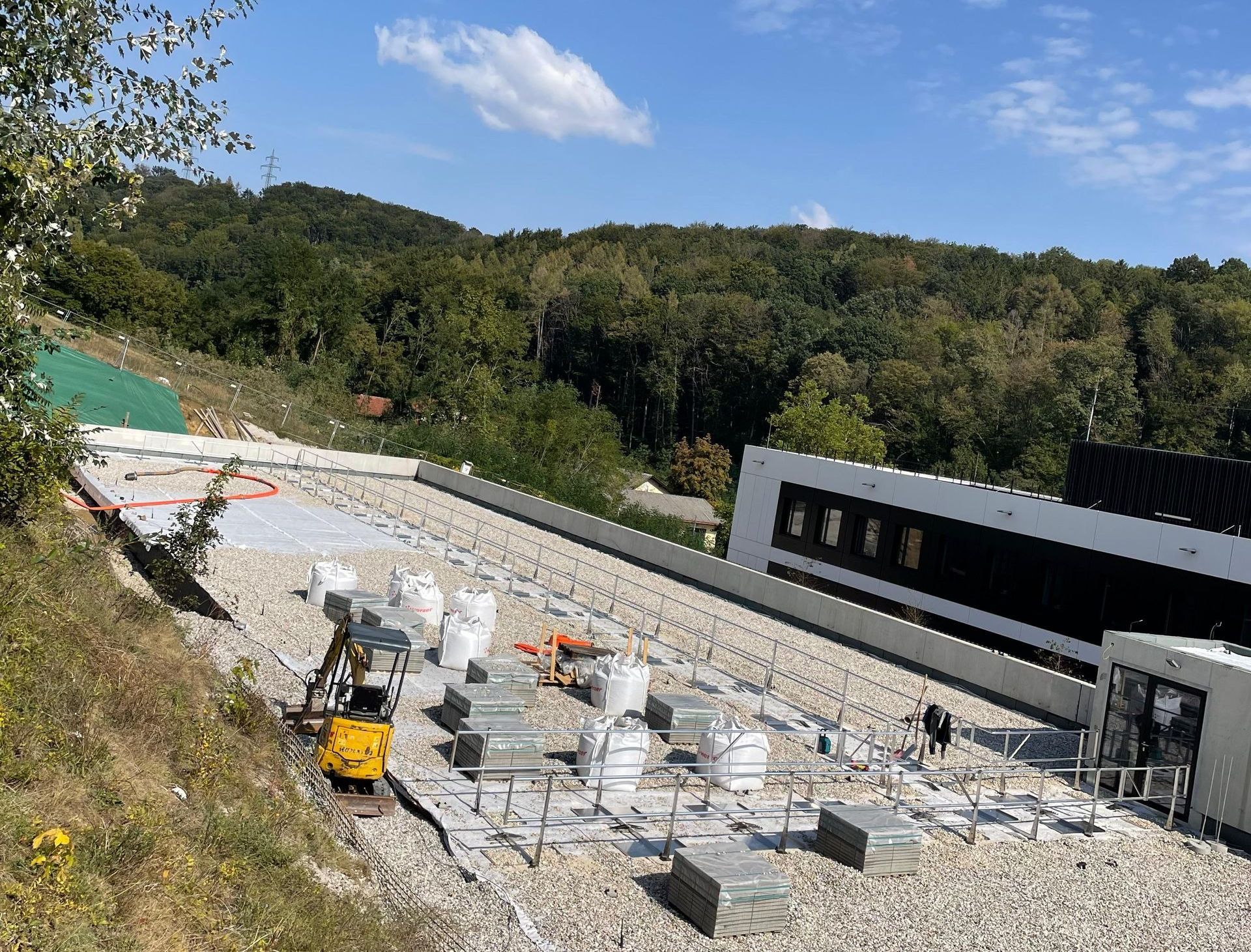 Auf einem Kieshügel wird ein großes Gebäude errichtet.