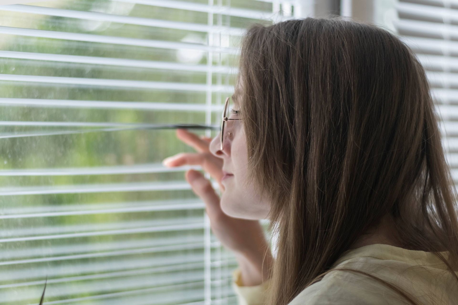 Someone looking through a set of blinds in their home at Accent Blinds near Lexington and Chapin, SC