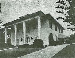 A black and white photo of a large house with columns.