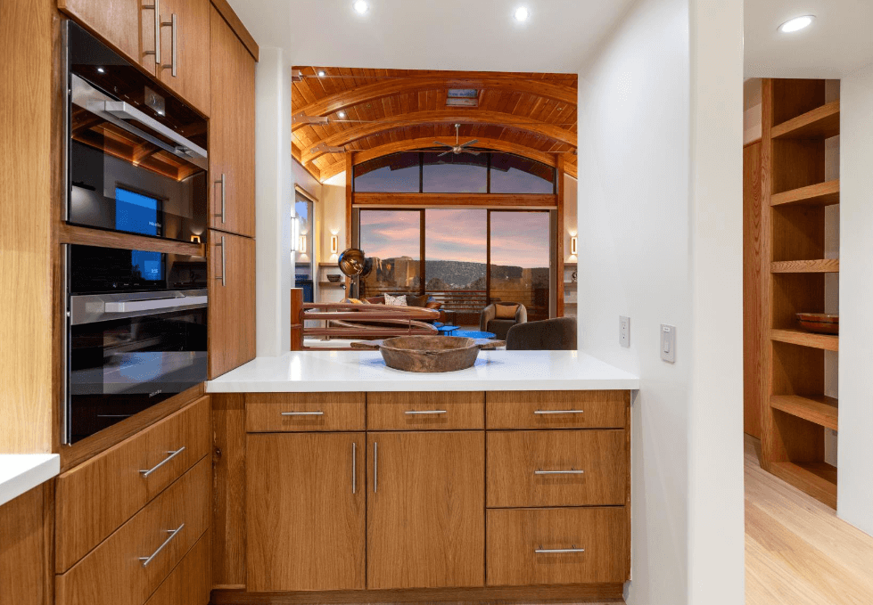 A kitchen with wooden cabinets and a large window.