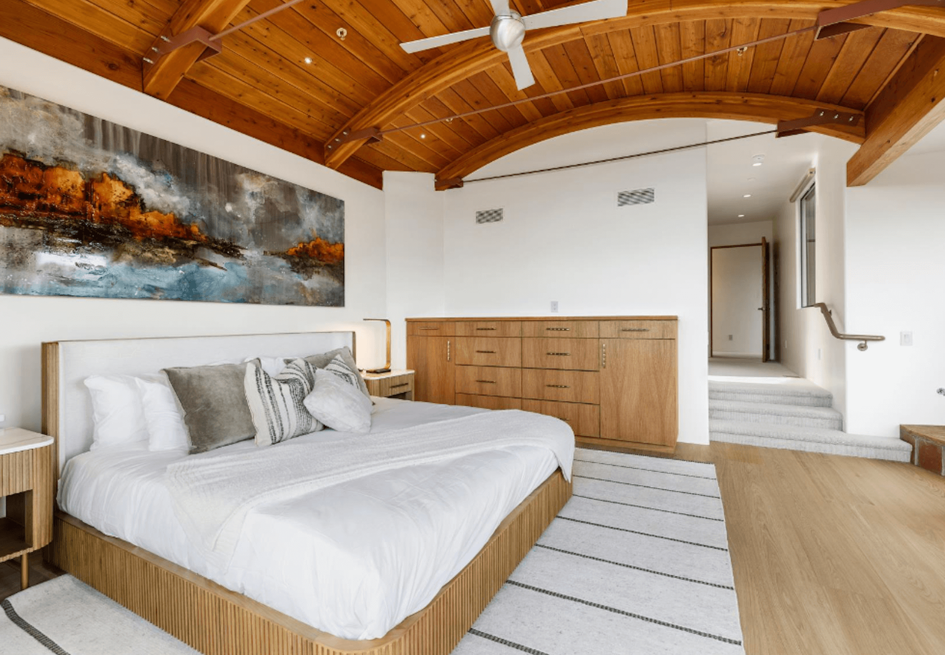 A bedroom with a large bed and a wooden ceiling.