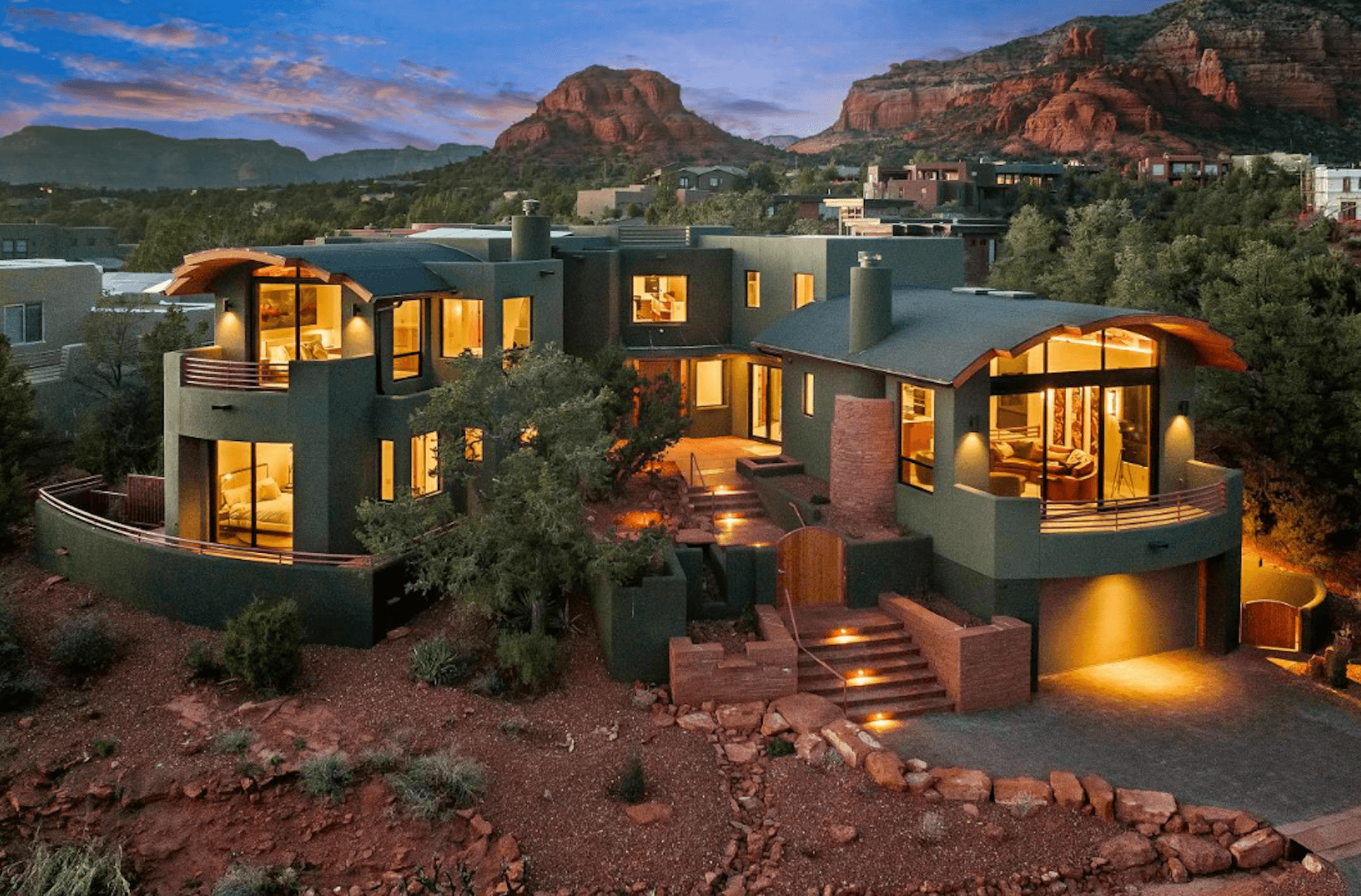 A large house with a mountain in the background is lit up at night