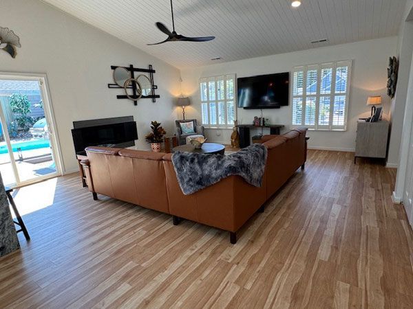 A living room with a large brown sectional sofa, a TV, and a view of a pool through a sliding glass door.