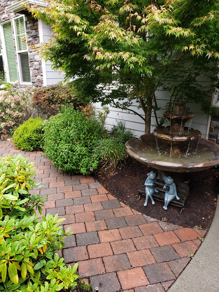 a brick walkway with a fountain in the middle of it